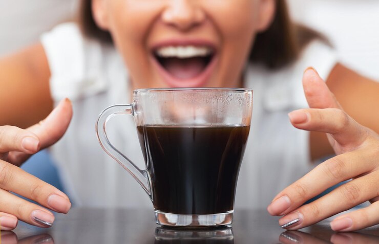 Foto meisje strekt zich uit naar een kop koffie binnen geknipt