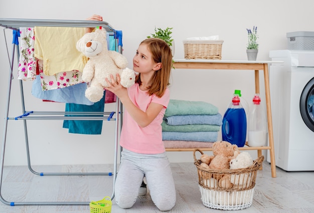 Meisje teddybeer opknoping op droger met pin in lichte wasruimte