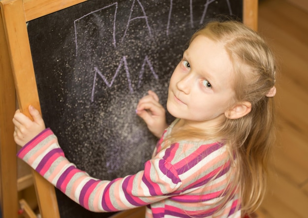 Foto meisje tekent op een ezel in de kinderkamer