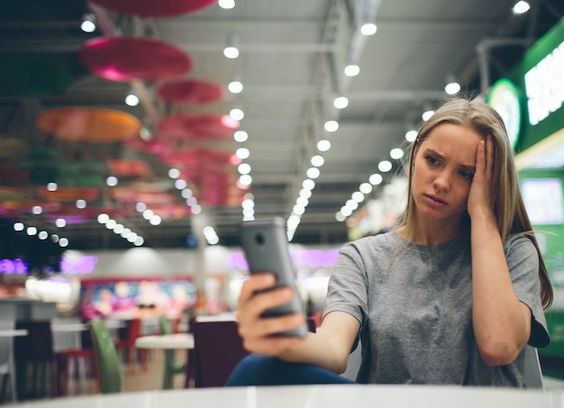 Meisje texting op de slimme telefoon op het terras van een restaurant