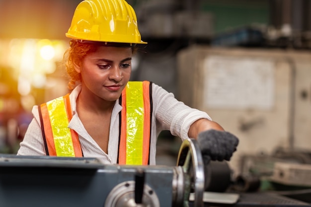 Meisje tiener werknemer Afro-Amerikaanse arbeidskrachten in industrie fabriek met zware stalen machine.