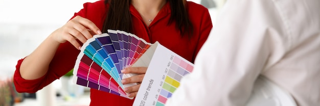 Meisje toont bouwerpalet trendy kleuren 2020. Pleisterwerk en gebruik brede paletkleuren. Vrouwelijke ontwerper biedt keuze kleuren voor renovatie van appartementen. Kies een paletkleuren voor interieur