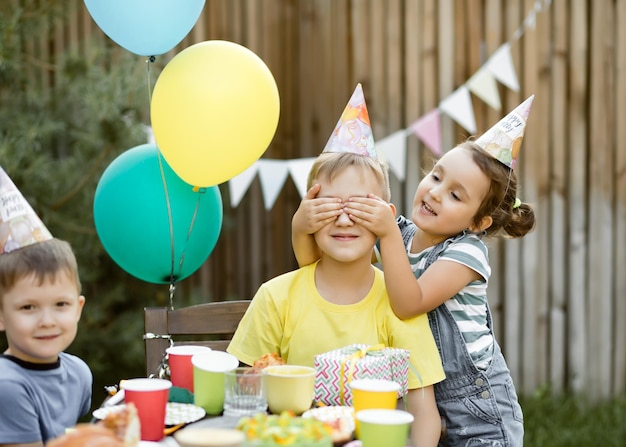 Meisje van achter sluit ogen broer of vriend met handen. verjaardagsfeest.