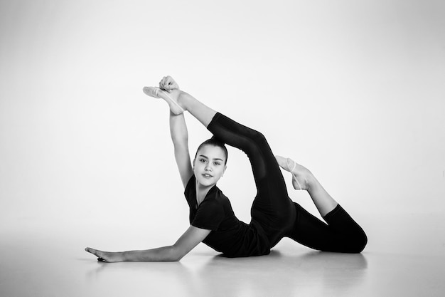 Meisje van ritmische gymnastiek in een bodysuit laat zich uitrekken op de grond