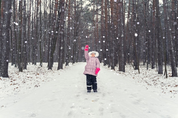 Meisje vangt sneeuwvlokken in sneeuwval in winter park