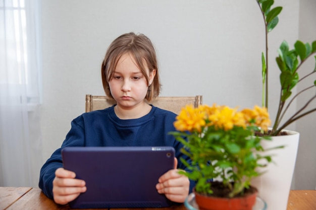 Meisje verloofd op tablet op afstand van thuis aan tafel