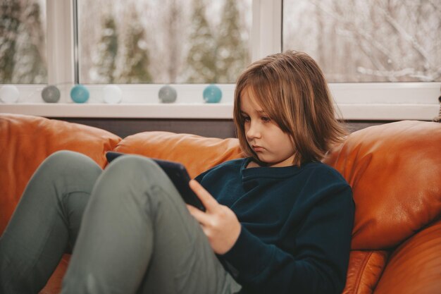 Meisje verloofd op tablet zittend op de bank in de woonkamer