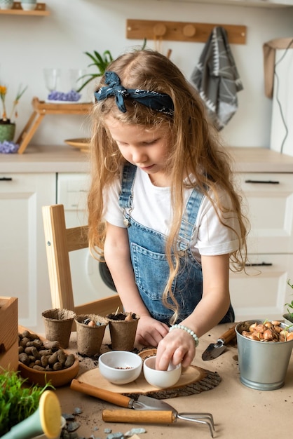 Meisje verplant bloemen en kamerplanten een kind in een bandana plant bollen hyacinten zaden