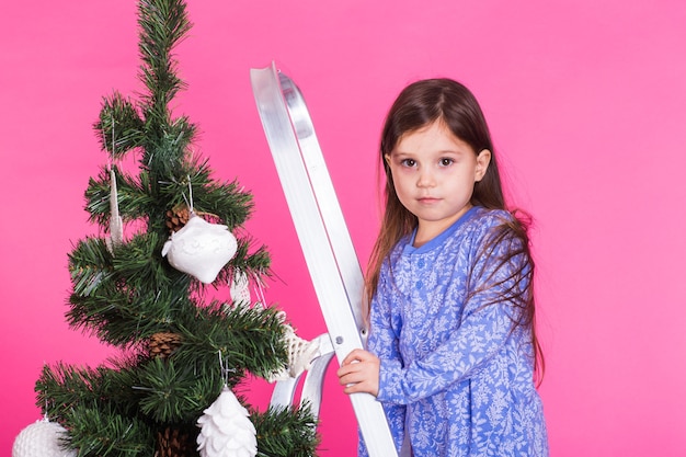 Meisje versieren kerstboom op roze