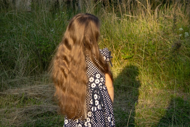 Meisje, vijf, in donkere jurk doet een stap achteruit en pronkt met haar lange bruine haar.