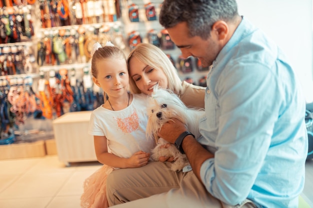 Meisje voelt zich gelukkig als ze met mama en papa naar de dierenwinkel komt