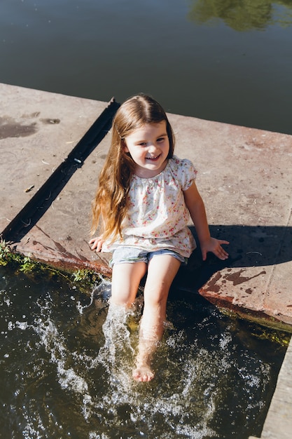 Meisje voeten in het water dompelen en lachen