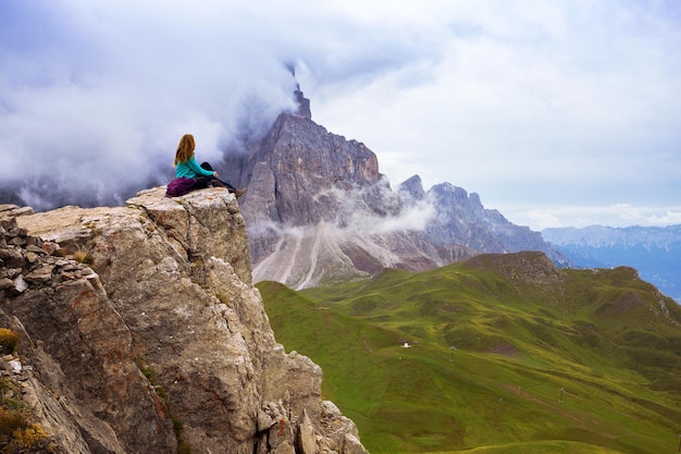 Meisje wandelaar zit aan de rand van de rots. Dolomieten, Italië.