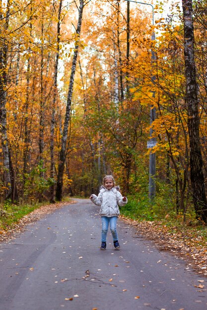 meisje wandelen in herfst bos in witte kleren in de weg
