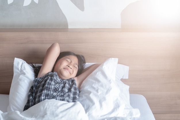 Meisje wordt wakker en strekt zich uit op bed in de ochtend