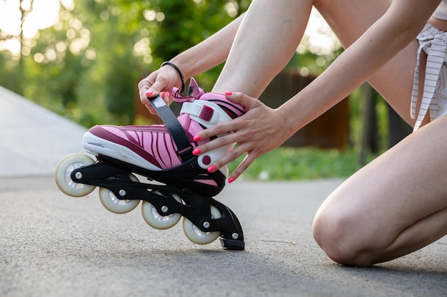 Foto meisje zet rolschaatsen op knielend op asfalt steegje