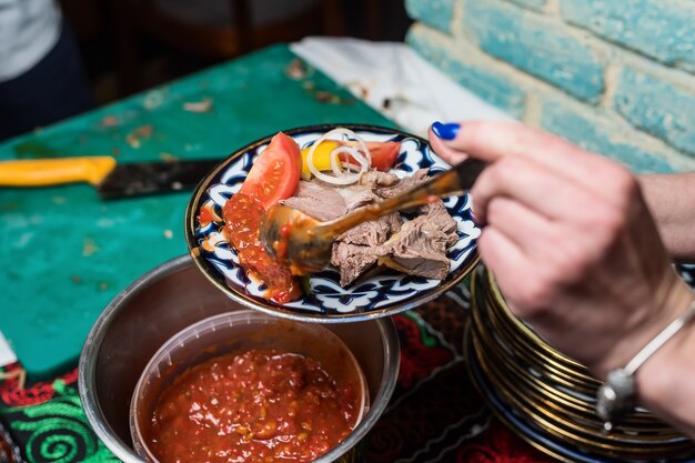 Meisje zet saus op een bord met vlees en groenten