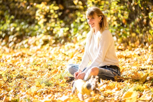 Meisje zit en ontspant op de grond in het herfstbos met koffie