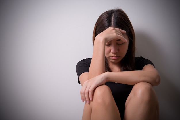 meisje zit in een depressie op de vloer in de buurt van de muur