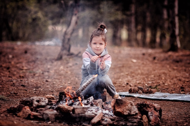 Meisje zit in het bos voor het vuur