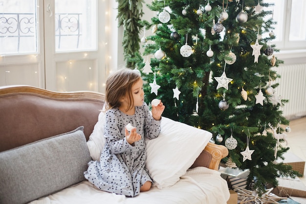 Meisje zit naast de kerstboom thuis