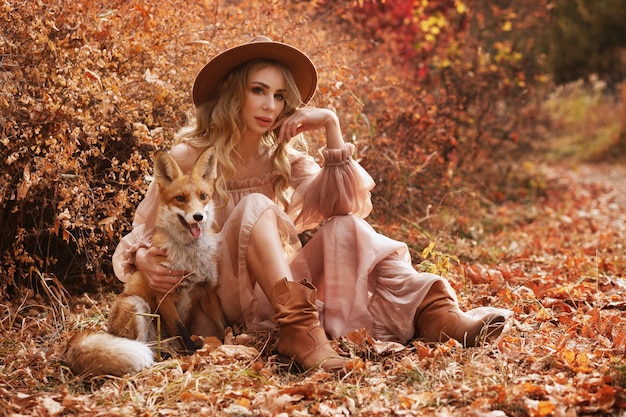 Meisje zit naast rode vos in de herfst
