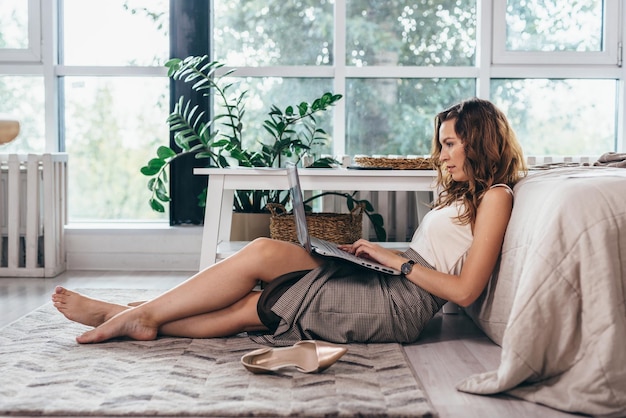 Meisje zit ontspannen op de grond met een laptop op schoot