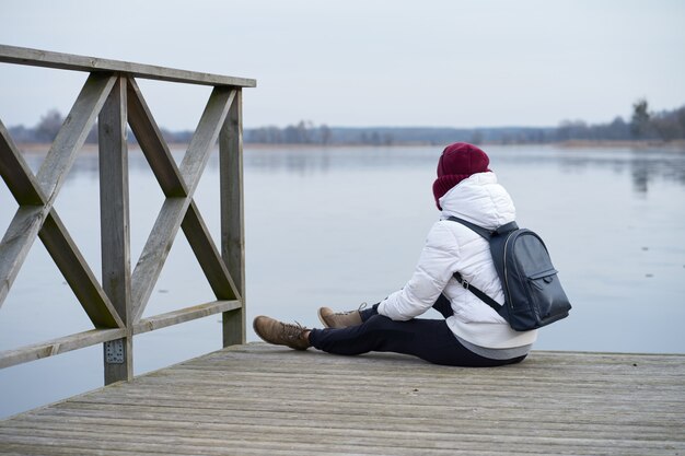 Meisje zit op een pier van winter ijsmeer tijdens reizen