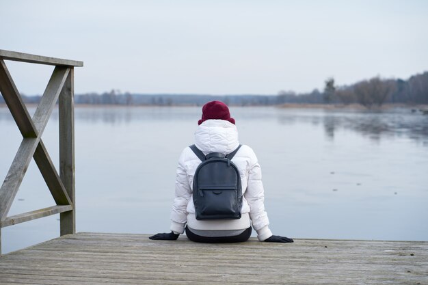 Meisje zit op een pier van winter ijsmeer tijdens reizen