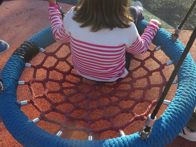 Foto meisje zit op een schommel op de speeltuin