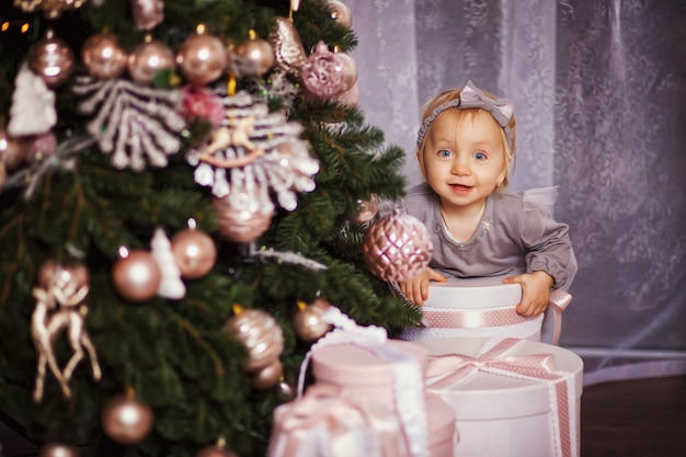 Meisje, zittend onder de kerstboom. Ze omhelst haar handen kerstcadeau dozen