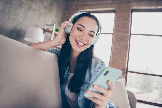 meisje zittend op de bank muziek luisteren en kijken naar telefoon