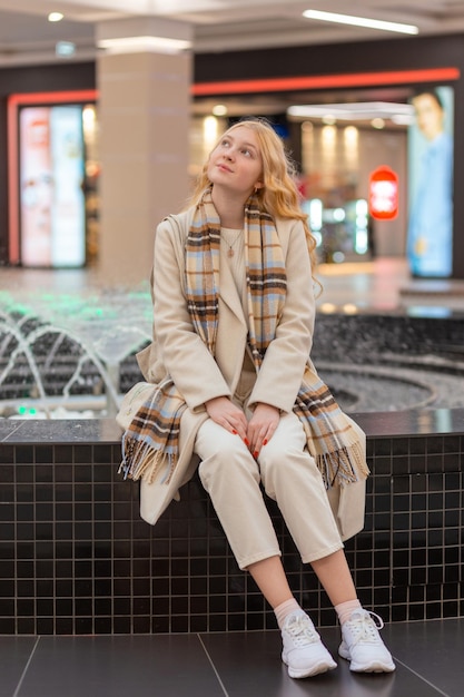 Meisje zittend op de borstwering in het winkelcentrum bij de fontein