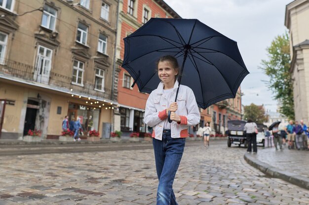 Meisjekind die met een paraplu op een stadsstraat lopen