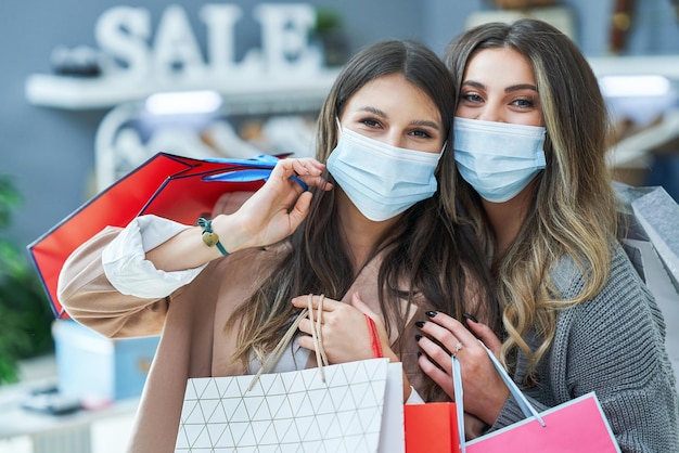 Meisjes bij het winkelen in de winkel met kleding die maskers draagt. Hoge kwaliteit foto