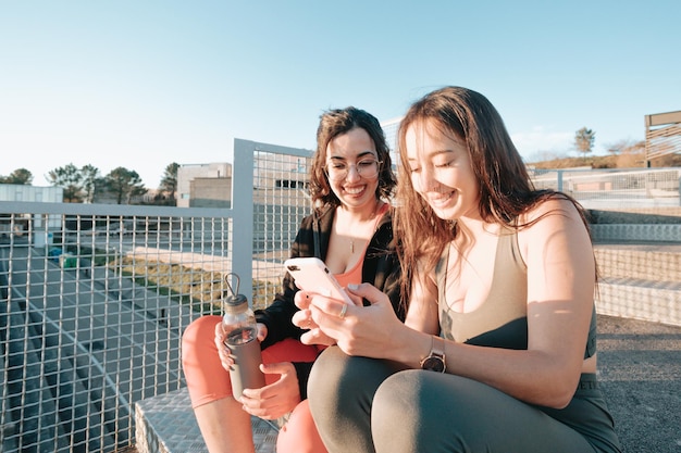 Meisjes die een selfie nemen terwijl ze rusten van het trainen op trappen, moderne sportieve jongeren die een video opnemen voor sociale netwerken terwijl ze glimlachen. Goede vibes en geluk concept. Afrikaanse meisjes