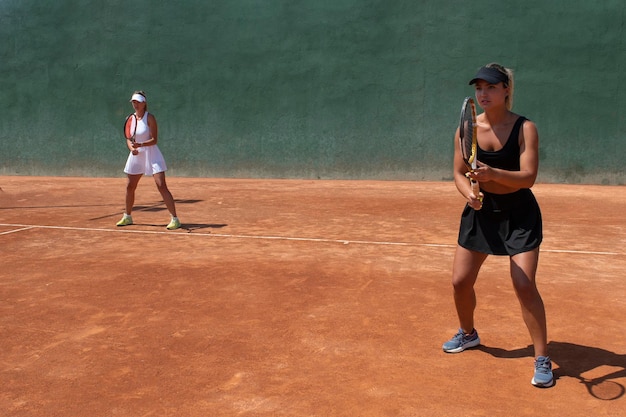 Meisjes die een tennisdubbelspel spelen op een gravelbaan