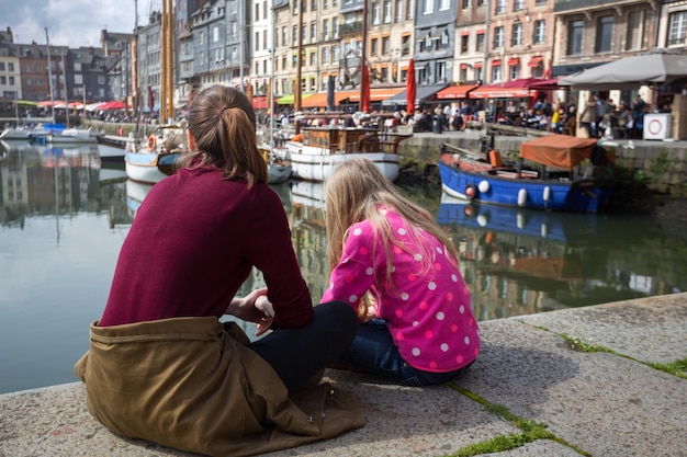 Meisjes die op achtergrond beroemde Franse stad Honfleur zitten