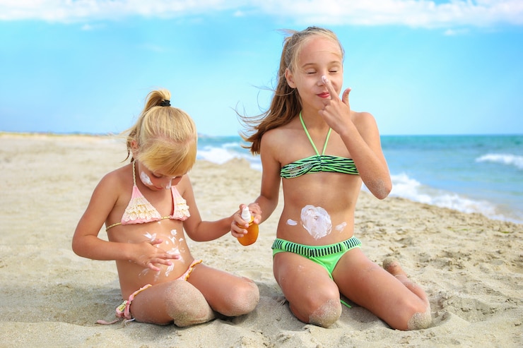 Meisjes die zonnebrandcrème toepassen bij het strand