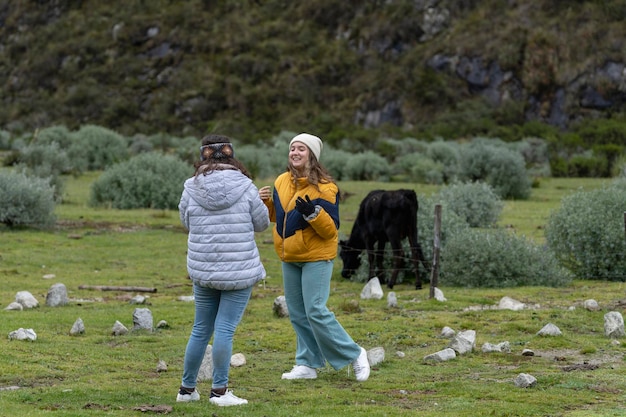 Meisjes glimlachen en praten naast een koe in de bergen