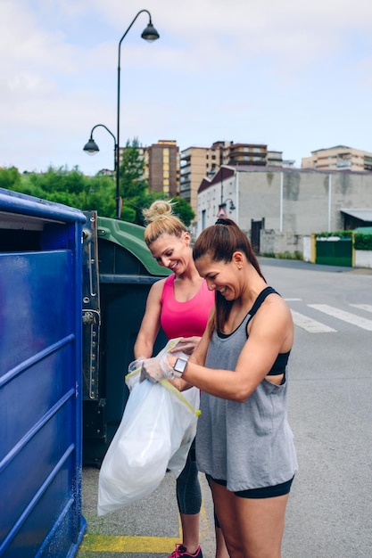 Meisjes gooien afval naar de recyclingcontainer