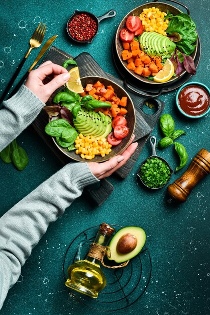 Meisjes handen houden een kom met een vegetarisch ontbijt pompoen avocado maïs en tomaten schoon eten veganistisch voedsel concept Top view