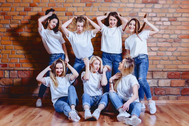 Meisjes in jeans bij achtergrond van bakstenen muur
