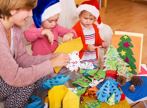 meisjes in Santa hoeden en lachende moeder doet applique werk