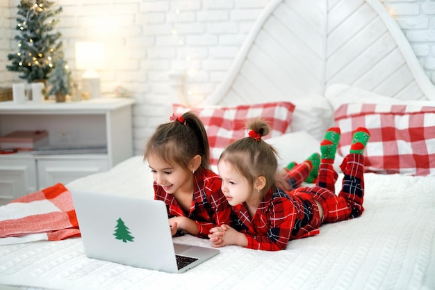 Meisjes kijken naar de laptop die lief lacht in bed met kerstdecor