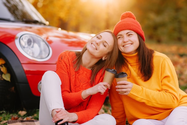 Meisjes lopen in herfstpark in rode auto herfststemming concept