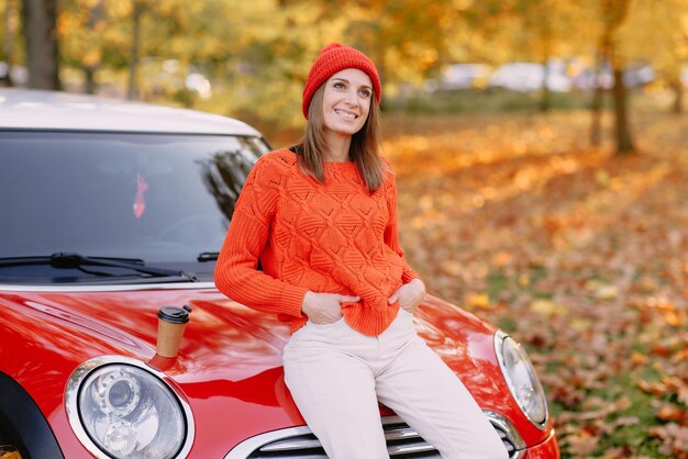 Meisjes lopen in herfstpark in rode auto herfststemming concept