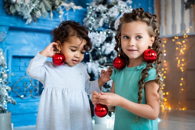 Meisjes met een donkere en lichte huidskleur spelen onder de kerstboom. schattige baby, Afrikaans meisje.