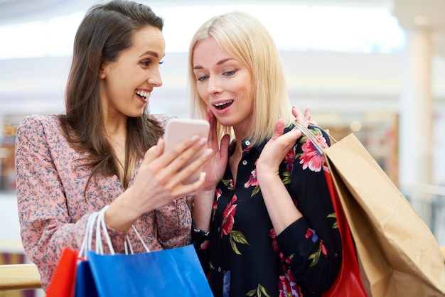 Foto meisjes met mobiele telefoon die de volgende winkelrichting kiezen