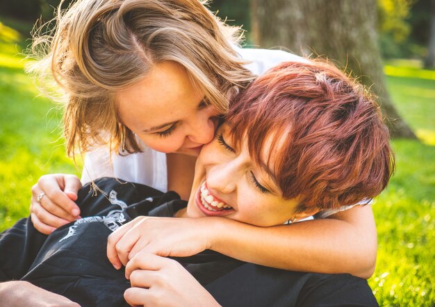 Meisjes verliefd kussen zittend op het gras in een park op een zonnige dag